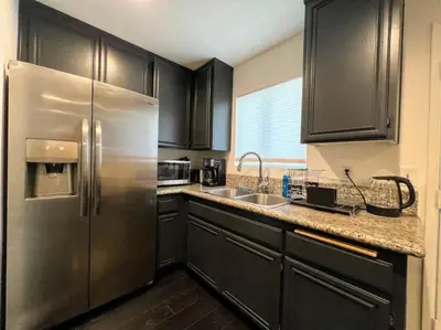 a kitchen with black cabinets and a stainless steel refrigerator at 2BR Suite in the Heart of Hollywood -BR5 in Los Angeles
