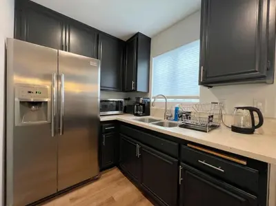 a kitchen with black cabinets and a stainless steel refrigerator at Trendy 2BR Near Hollywood Hotspots - BR9 in Los Angeles