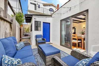 a patio with a blue couch and chairs at Historic Spanish Home at Hollywood Beach in Oxnard