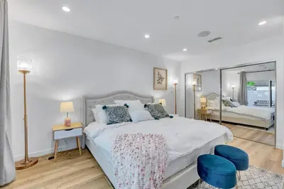 a white bedroom with a large bed and two blue stools at LA Home near Universal Studios and Hollywood in Los Angeles