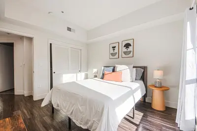 a white bedroom with a bed and a table at Outstanding 2BDR in SM- 5-15 mins to the beach! in Los Angeles
