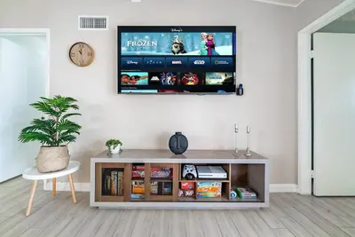 a living room with a tv on a wall at Dino Disneyland by OC Adventure Homes in Garden Grove