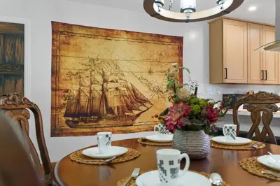 a dining room table with a painting of a ship at Pirate Cove by OC Adventure Homes in Garden Grove