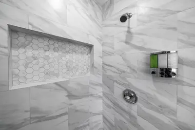 a bathroom with a shower with white marble at Pirate Cove by OC Adventure Homes in Garden Grove