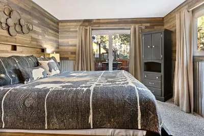 a bedroom with a bed and a wooden wall at Green Pines Lake Retreat Walk to Lake in Big Bear Lake