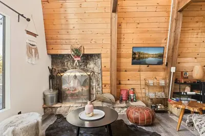 a living room with a fireplace and a table at Lucky Bear Cabin in Big Bear Lake