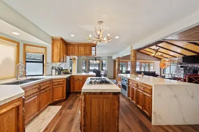 a large kitchen with wooden cabinets and a chandelier at Roaring Lion Lakefront Lodge in Big Bear Lake