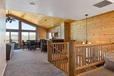 a living room with wooden walls and a kitchen and a dining room at Sky High Mountain Lodge Lake View in Big Bear Lake