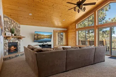 a living room with a large couch and a fireplace at Sky High Mountain Lodge Lake View in Big Bear Lake