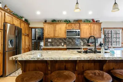a kitchen with wooden cabinets and a kitchen island with stools at Snowcrest Lodge in Exclusive Fox Farm in Big Bear Lake