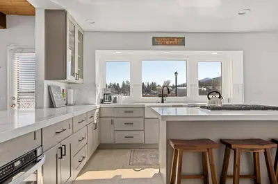 a kitchen with white cabinets and a large window at HoneyBear Lodge Lakefront in Big Bear Lake