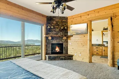a bedroom with a fireplace and a large window at Hidden Haven Estate in Big Bear Lake
