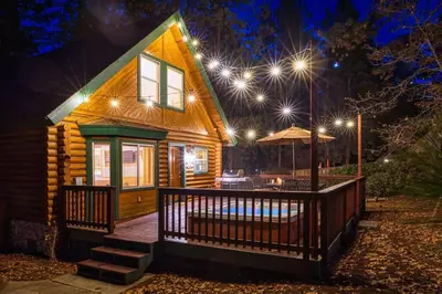 a wooden house with a deck at night with lights at Bear Kub Kabin in Big Bear Lake