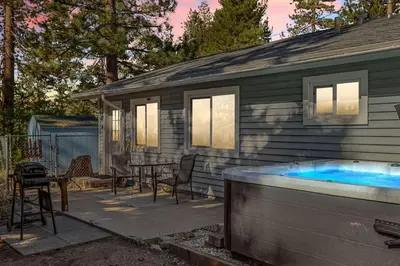 a patio with a hot tub next to a house at Fawnskin Forest Haven in Fawnskin