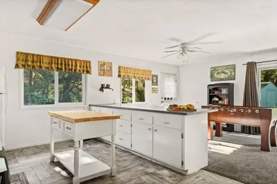 a kitchen with white cabinets and a table and a piano at Fawnskin Forest Haven in Fawnskin