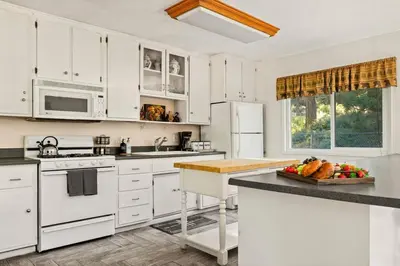 a kitchen with white cabinets and a bowl of fruit on a counter at Fawnskin Forest Haven in Fawnskin