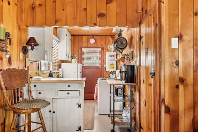 a kitchen with wooden walls and white cabinets and a counter at Tree Top Ranch in Big Bear Lake
