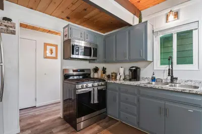 a kitchen with gray cabinets and a stove top oven at The Teddy Bear Cabin! Large Patio! in Big Bear City
