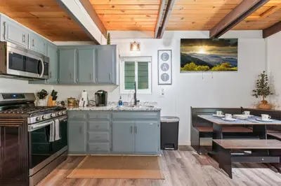 a kitchen with blue cabinets and a table in it at The Teddy Bear Cabin! Large Patio! in Big Bear City