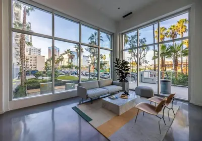 a living room with a couch and chairs and large windows at @ Marbella Lane - Grand 2BR w/ Beach & Ocean Views in Long Beach
