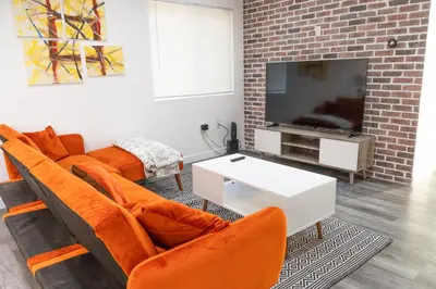 a living room with orange chairs and a flat screen tv at Beautiful hillside gateway in Los Angeles