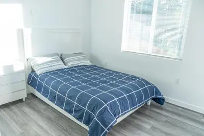 a white bedroom with a bed with a blue comforter at Beautiful hillside gateway in Los Angeles