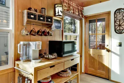 a living room with a tv and a table with a television at Kozy Cabin Big Bear~ Walk to Village & Lake Cottage~ in Big Bear Lake