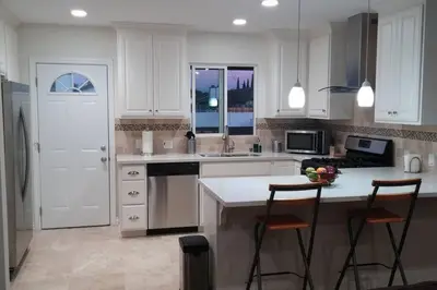 a kitchen with white cabinets and a counter with two chairs at Family getaway 3 BR 2 Bath home in Lomita, CA. in Los Angeles