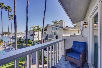 a balcony with a blue chair and palm trees at Huntington Beach Condo - Walk to the Ocean! in Huntington Beach