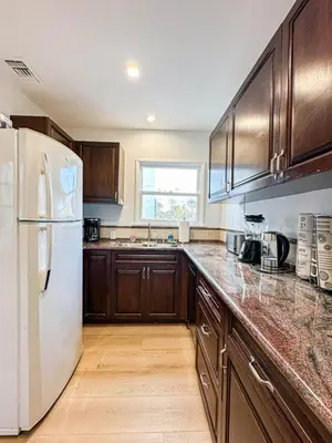 a kitchen with a white refrigerator and wooden cabinets at Modern 2-Bedroom Gem Close to Beverly Hills - DOH2 in Los Angeles