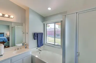 a bathroom with a tub and a sink and a window at Victorville Home with Fenced Backyard and Patio! in Victorville