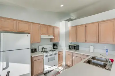 a kitchen with wooden cabinets and a white refrigerator at Victorville Home with Fenced Backyard and Patio! in Victorville