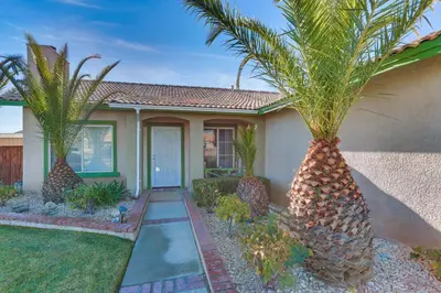 a house with palm trees in front of it at Victorville Home with Fenced Backyard and Patio! in Victorville