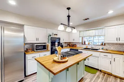 a kitchen with white cabinets and a stainless steel refrigerator at Creekside Cabin in Crestline