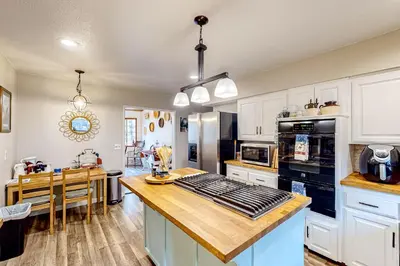 a kitchen with white cabinets and a wooden counter top at Creekside Cabin in Crestline