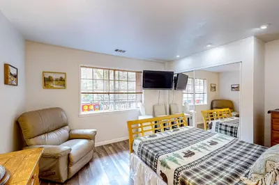 a bedroom with a bed and a couch and a chair at Creekside Cabin in Crestline