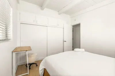 a white bedroom with a bed and a chair at NEW! Ocean View Mid-Century Modern Beach House in Manhattan Beach