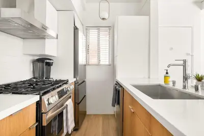 a white kitchen with a stove and a sink at NEW! Ocean View Mid-Century Modern Beach House in Manhattan Beach