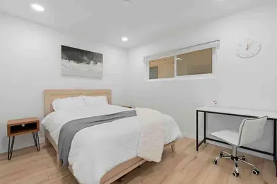 a bedroom with a bed and a desk and a chair at Brand New Ocean-View Beach Home Steps to the Sand! in Manhattan Beach
