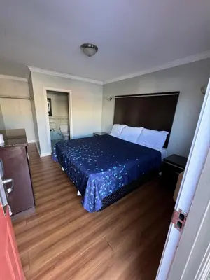 a hotel room with a bed with a blue bedspread at La Cienega Inn Motel in Los Angeles