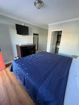 a bedroom with a bed with a blue blanket on it at La Cienega Inn Motel in Los Angeles