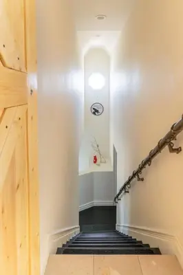 a hallway with a staircase with a clock on the wall at Epic Views! Hollywood Hills SkyVilla: Crow's Nest in Los Angeles