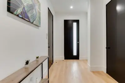 a hallway with white walls and a black door at Brand New Modern 5 Bedroom House Pickfair Village in Los Angeles