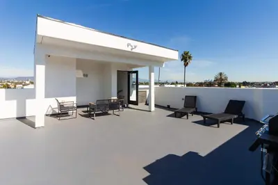 a patio with chairs and tables on a roof at Brand New Modern 5 Bedroom House Pickfair Village in Los Angeles