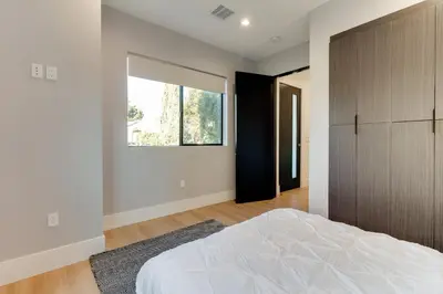 a bedroom with a bed and a large window at Brand New Modern 4 Bedroom House Pickfair Village in Los Angeles