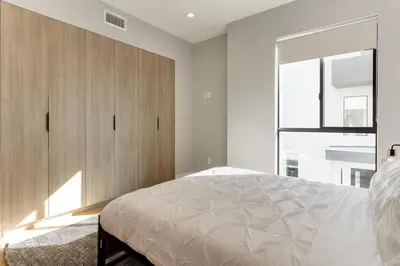 a bedroom with a bed and a large wooden cabinet at Brand New Modern 4 Bedroom House Pickfair Village in Los Angeles