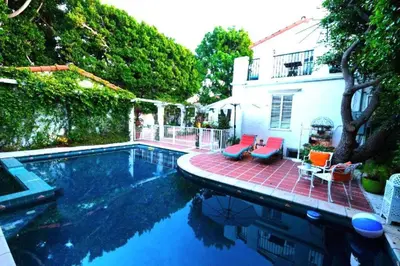 a swimming pool with two chairs and a house at Beverly Hills Celebrity Home in Los Angeles