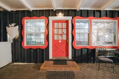 a room with two windows and a red door at Arrowhead Tree Top Lodge in Lake Arrowhead