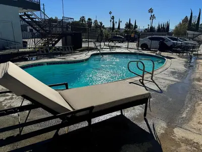 a swimming pool with a chair in front of it at Sands Motel in Riverside