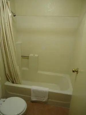 a bathroom with a toilet and a bath tub and a toilet at Economy Inn in Victorville